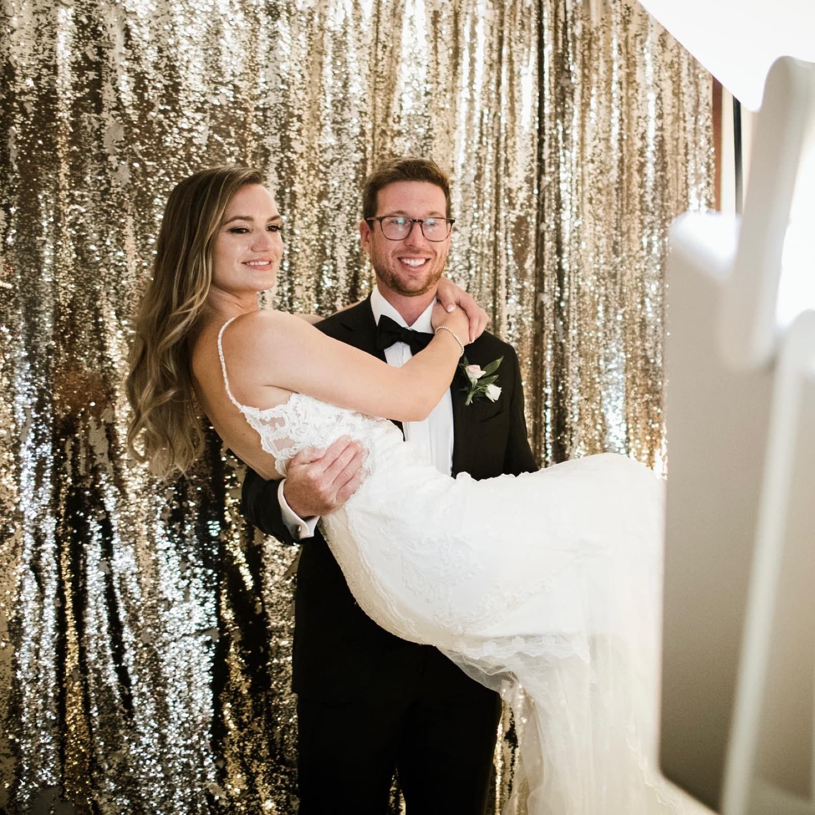 Bride and groom photographed against the gold sequin backdrop